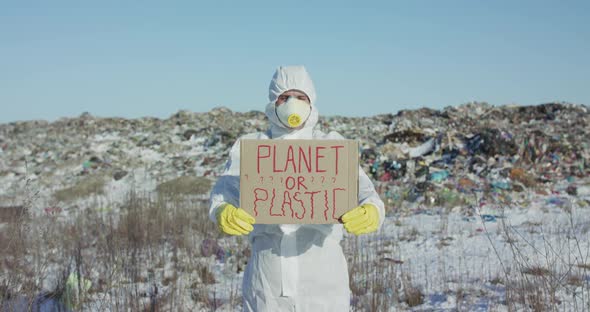 Man Shows Protest Sign Planet or Plastic Against Huge Plastic Landfill