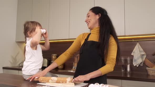 Cute Little Girl and Her Beautiful Mom Holding Eggs on Her Eyes and Smiling While Cooking in Kitchen