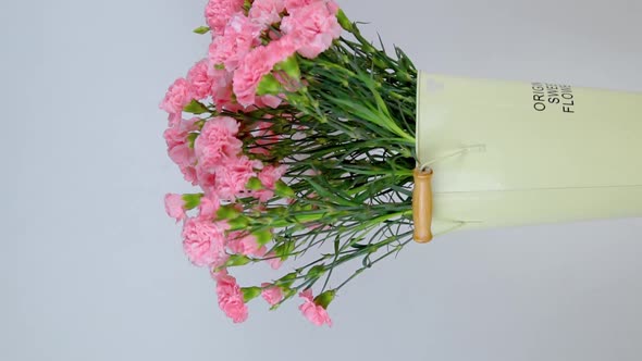 Close-up of a large number of pink carnations in a tin vase rotating.