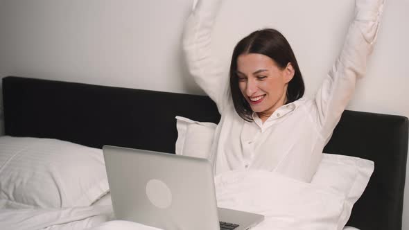 Excited Woman Has Good News Using Laptop on Bedroom