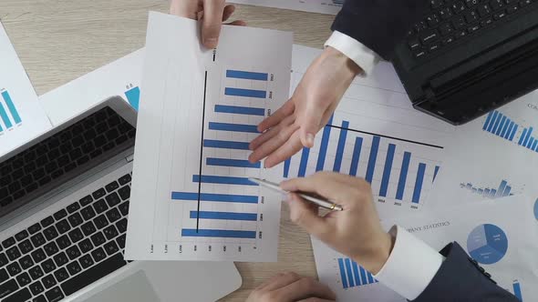 Two Men in Suits Discussing Company Statistics, Showing Graph Document, Business