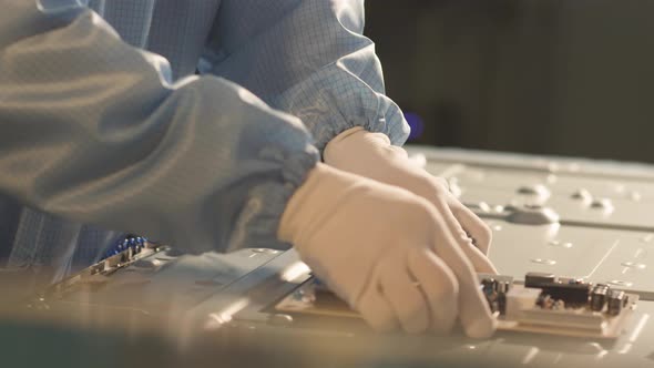 worker installs an electronic board on the back of a TV