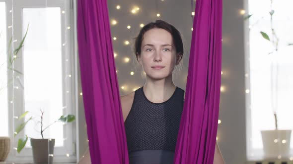 Young Smiling Woman Walks to a Yoga Hammock and Looks in the Camera