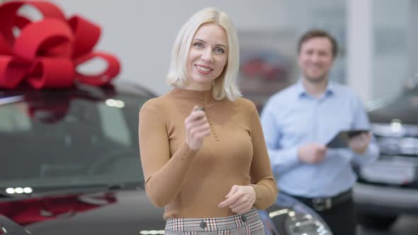 Middle Shot of Confident Satisfied Female Buyer Turning To Camera Smiling and Stretching Car Key