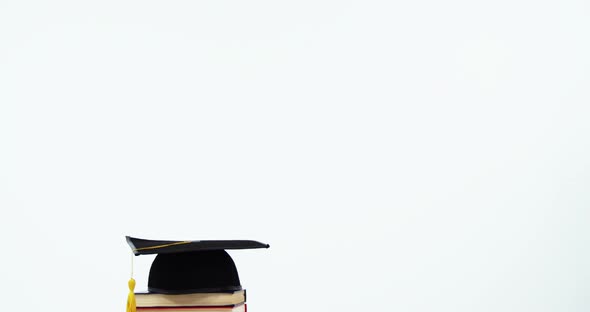 Close-up of mortar board and stack of books