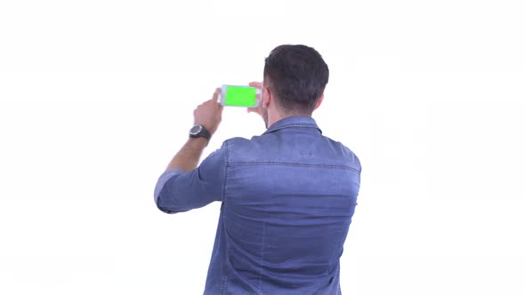 Rear View of Young Bearded Hipster Man Taking Picture with Phone