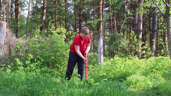 A Young Boy Mows Green Grass with an Electric Trimmer