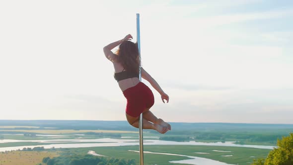 Pole Dance on Nature - Young Woman in Sports Clothes Spinning on the Pole with Her Legs