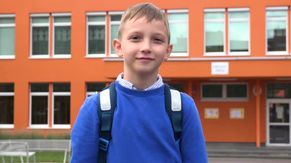 A Young Boy Smiles and Motions To the Camera in a Gesture of Invitation - an Elementary School