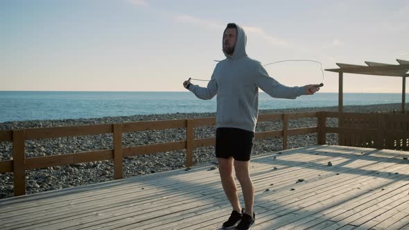 Tired Man Is Throwing Skipping Rope During Exercise on Sea Shore in Daytime