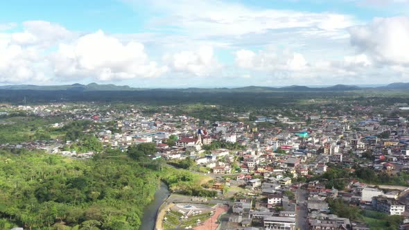 Going down from a high view of a city that is located in the mountains and surrounded by forest 