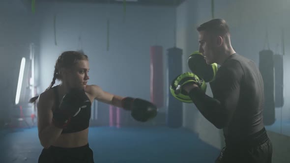 Female Fighter Trains Punches and Defence Punching Focus Mitts Training Day with a Man Trainer in