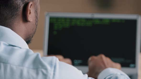 Back Rear View of Unrecognizable African Young Man Working at Computer IT Programmer Engineer