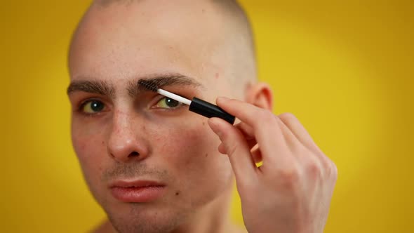 Closeup Face of Confident Male Transgender Applying Mascara Looking at Camera