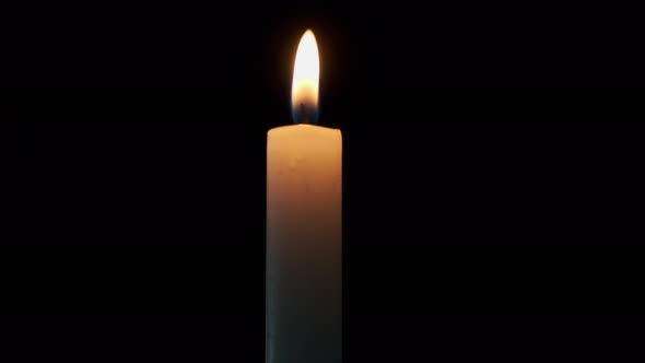 Footage Candle Burns on a Black Background and Blows the Flame