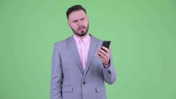 Stressed Young Bearded Businessman Using Phone and Getting Bad News