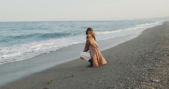 Young girl with black boots has fun on the beach near the sea in Italy