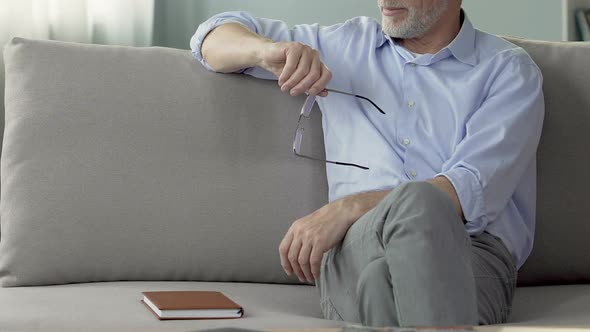 Experienced male psychologist sitting on couch, listening to patient, session