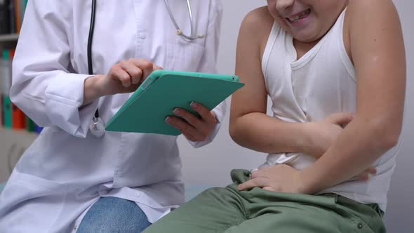Unrecognizable Boy Complaining Stomach Ache in Hospital As Doctor Filling in Online History