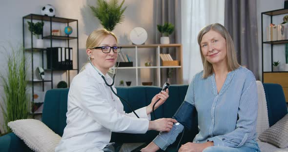 Doctor Measuring Blood Pressure and then Looking Into Camera