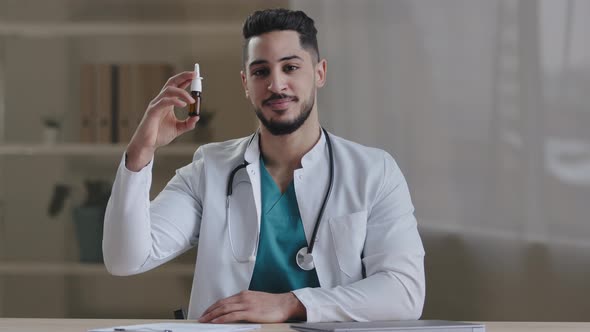 Arabian Young Male Doctor Hispanic Therapist Demonstrate at Camera Nasal Spray Medicine Remedy