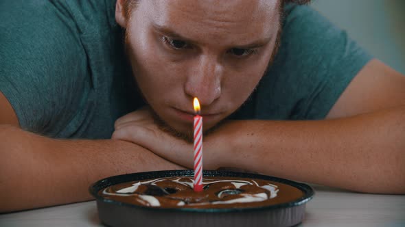 A Man Is Looking at a Candle on the Cake