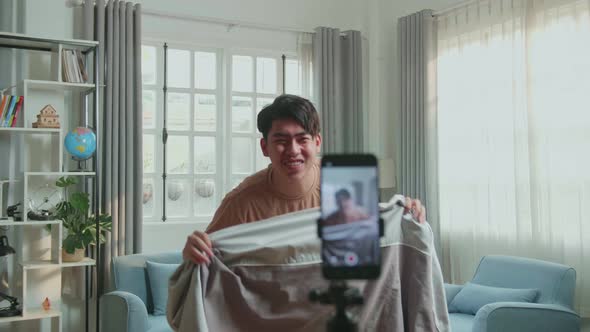 Asian Man Shows Trick With Disappearing On Mobile Phone For Social Networks In Cozy Room