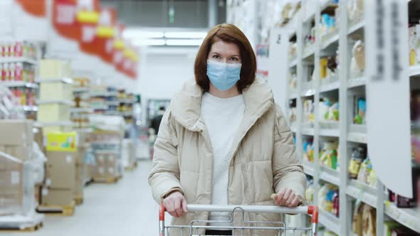 Woman in Mask Walking with Shopping Cart in Mall