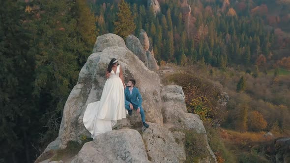 Newlyweds Stand on a High Slope of the Mountain