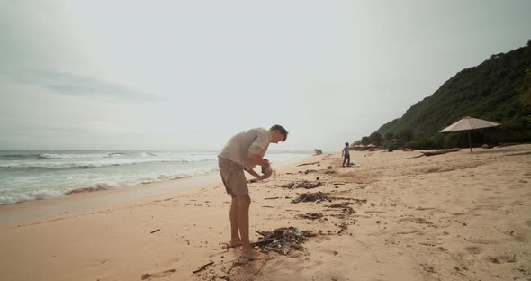 Close Up Circling View of a Young Caucasian Male Picking Up Trash on the Beach