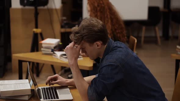 Side View of Focused Young Man Using Laptop at Library