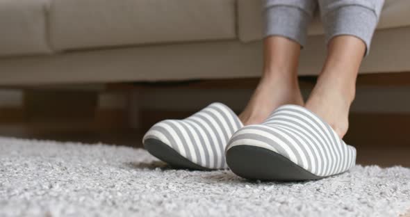 Woman wear fleece slippers and sit on sofa