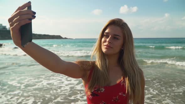 Portrait of Cute Young Woman with Blond Hair Taking Selfie on Her Cellphone at the Beach Close Up