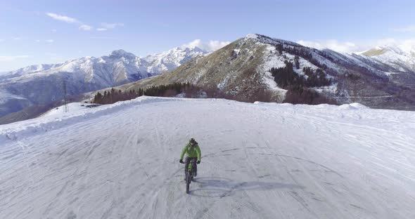 Backward Aerial Over Biker Man Cycling on Snowy Path During Winter with Mtb Ebike