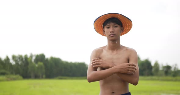 Young farmer topless standing and arms folded in rice field