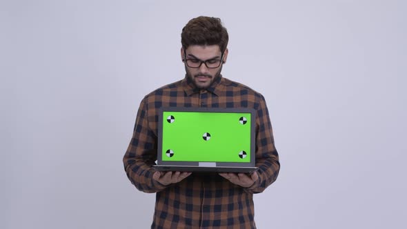 Happy Young Bearded Indian Hipster Man Showing Laptop