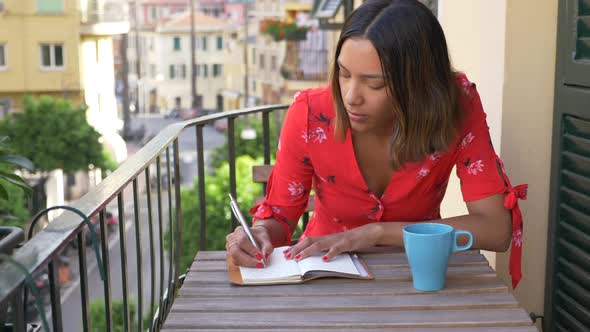 A woman writing in a journal diary traveling in a luxury resort town in Italy, Europe.