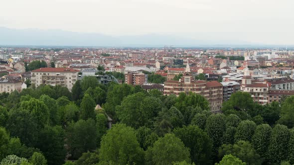 Green park with trees and cityscape of Turin on grey moody day, aerial drone view