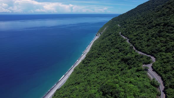 Flying along a narrow cliff-side highway overlooking a secluded tropical beach in Eastern Taiwan