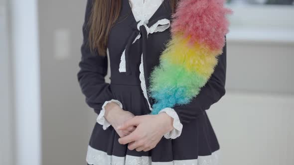 Camera Moves Up As Slim Caucasian Young Woman in Maid Uniform Standing Indoors with Colorful Dust