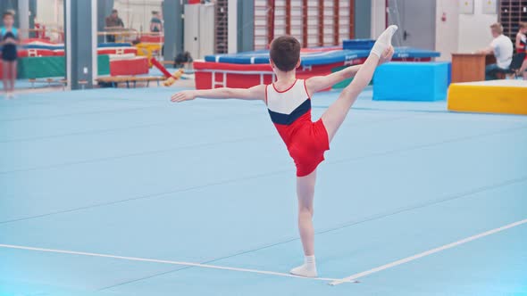 A Little Gymnastics Boy Stretching His Leg on the Sports Arena