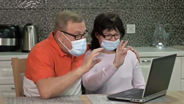 Cheerful Married Couple in Medical Masks Are Communicating with Someone Via the Internet