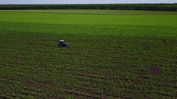 Shooting From Drone Flying Over Tractor with Harrow System Plowing Ground on Cultivated Farm Field