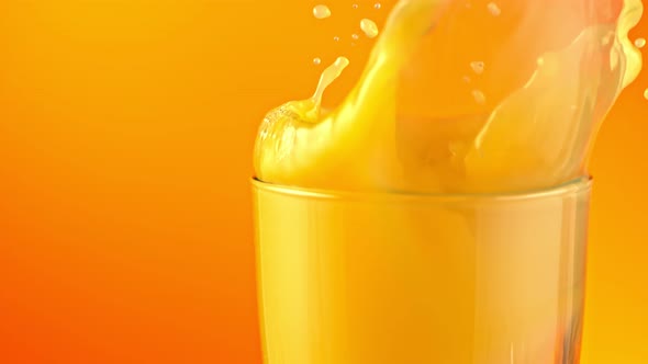 Super Slow Motion Shot of Ice Cubes Falling Into Glass of Orange Juice and Making Splash at 1000Fps