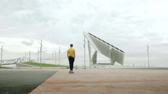 Young Attractive Trendy Man skateboarding fast under a solar panel on a morning sunny day with an ur