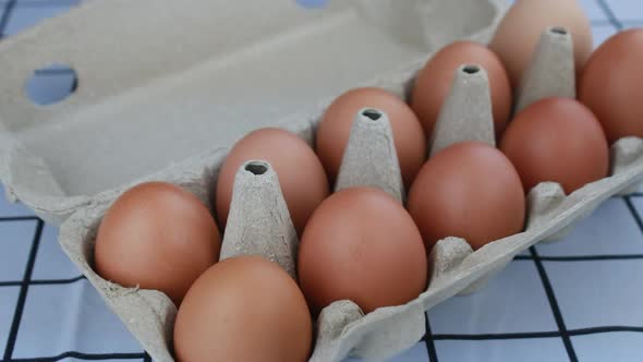 Woman hand pick up fresh chicken eggs from an egg tray.