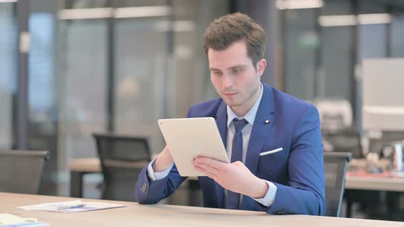 Businessman Using Tablet While Sitting in Office