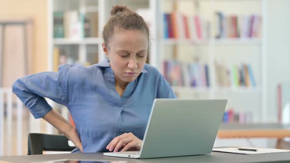 Tired African Woman with Laptop Having Back Pain in Library