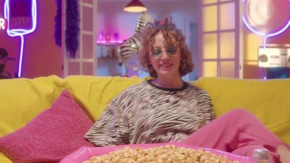 Portrait of Trendy Girl Eating Popcorn on Sofa in Party Room