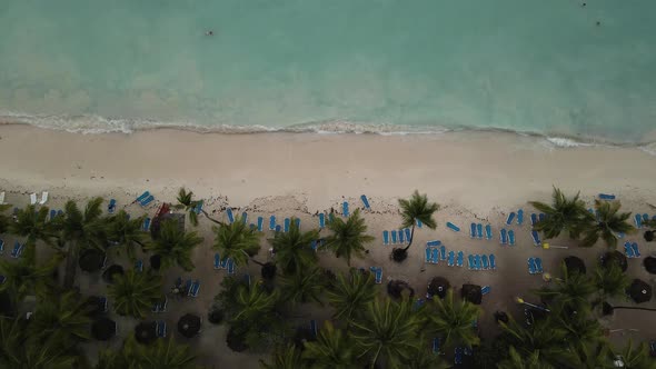 Shore Of A Tourist Beach With Sun Loungers And Palm Trees